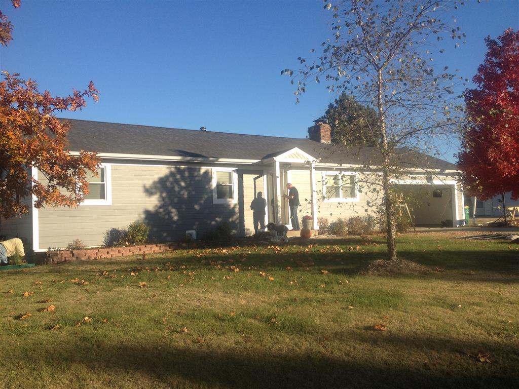 Image representing Gorilla Exteriors vinyl siding repair and installation services in Kansas City showcasing a man standing on a porch and the completion of new siding work on the front of a ranch home.