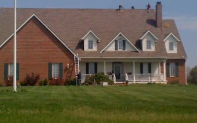 two people on a roof performing an inspection of the roof and shingles