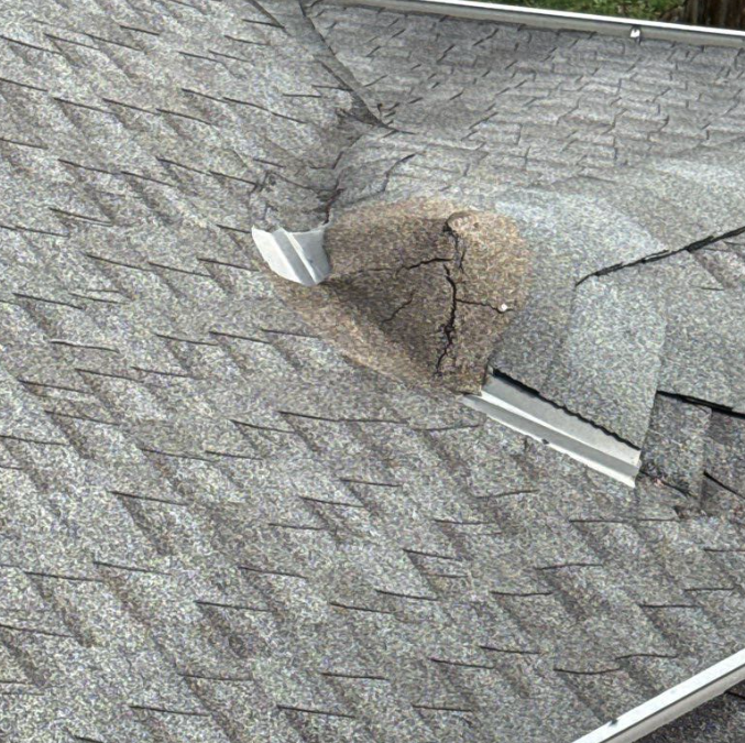 Damaged roof shingles with a visible crack, highlighting the need for urgent roof leak repair in Kansas City.